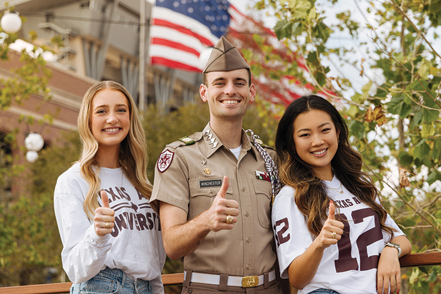 Aggie students in front of Kyle Field stadium and American flag